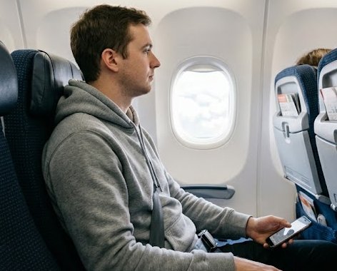 Passenger seated in an economy seat wearing a hoodie