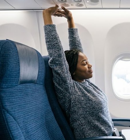 Lady streaching while seated on an aircraft